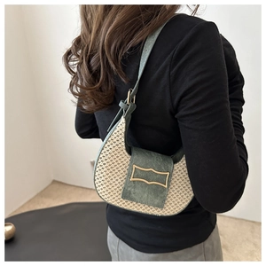 Detail of woven crescent shoulder bag with dark green suede flap and gold hardware