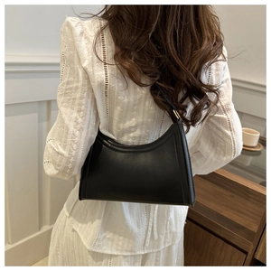 Chic black matte leather baguette bag shown from behind on a model shoulder