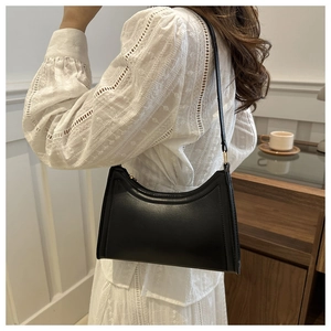 Classic black underarm baguette bag with smooth finish and curved stitching details