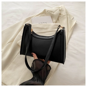 Close-up of black baguette underarm bag with gold metal hardware and smooth leather finish