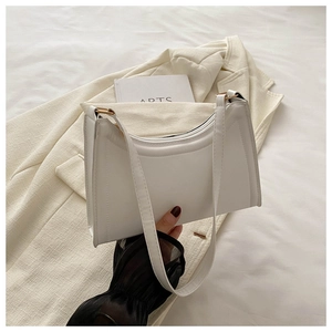 Close-up of minimalist white baguette bag on fabric with artsy aesthetic details