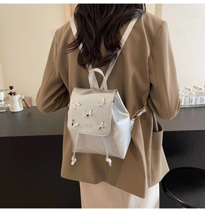 Detail of silver metallic mini backpack with butterfly hardware and drawstring closure