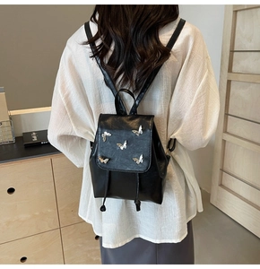 Mini black leather backpack with silver butterfly accents shown on model back