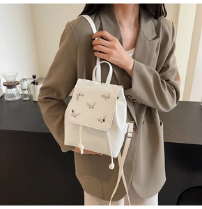 Detailed view of white PU mini backpack with silver butterfly metal charms and drawstring