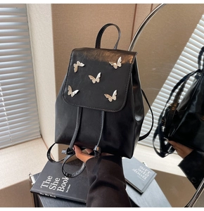 Close-up of black PU leather backpack with silver metal butterfly accents and drawstring
