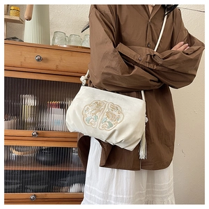 Detail van witte vintage satijnen crossbodytas met bloemenborduursel en kwastje