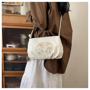 Detail van elegant rond bloemig borduurwerk op de beige crossbodytas voor dames