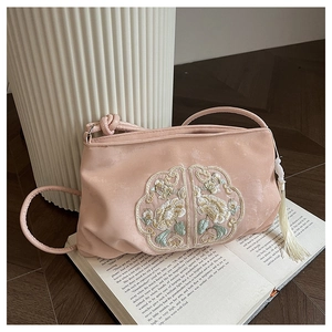 Detail van roze fluwelen crossbodytas met bloemenborduursel en witte franje kwastje