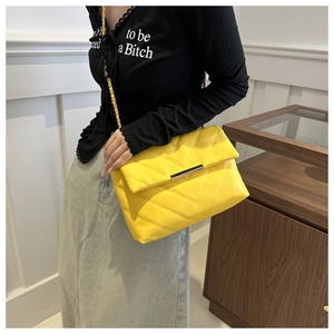 Detail of yellow V-quilted faux leather crossbody bag with elegant gold chain strap