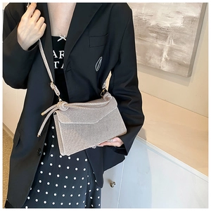 Detail of beige woven crossbody bag with decorative knot and slim shoulder strap
