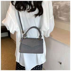 Detailed back view of a grey twill crossbody bag featuring gold hardware and a top handle