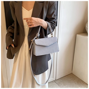 Detail showing grey-blue woven texture crossbody bag with unique chunky rope handle and gold rings