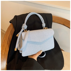 Detail of light blue twill fabric handbag featuring a unique knotted handle design