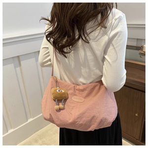 Detailed shot of pink nylon hobo bag with Fashion logo tag and brown plush doll charm