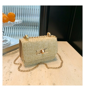 Close-up of beige woven straw texture with a golden metal rotary clasp and chain strap