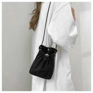 Detail of minimalist black drawstring bucket bag with silver metal toggle and thin strap