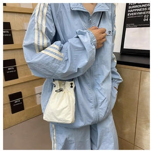 Detail view of cream mini drawstring bucket bag showing nylon texture and metal eyelets
