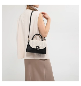 Detail of woven beige texture and black leather contrast on a stylish crossbody bag