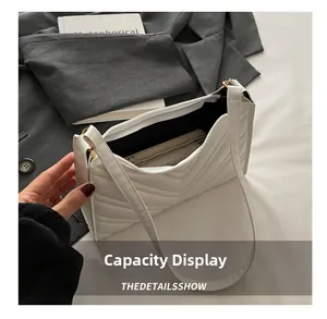 Gros plan de l'intérieur du sac à bandoulière matelassé blanc montrant la capacité