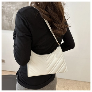 Détail du sac baguette blanc matelassé avec coutures en V et finition brillante