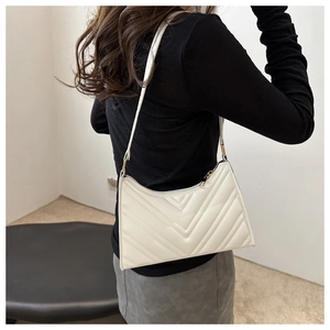 Détail du sac hobo beige avec matelassage en V et fermeture éclair porté à l'épaule