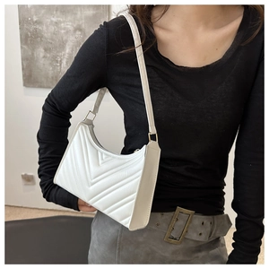 Détail du sac baguette blanc matelassé avec ferrures dorées porté à l'épaule
