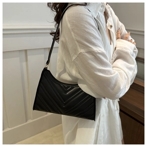 Détail du sac porté épaule matelassé noir avec coutures en V et finitions dorées