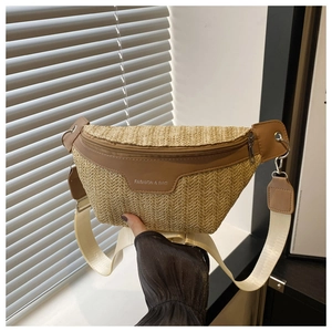 Detail of straw woven waist bag featuring brown leather trim and wide fabric strap
