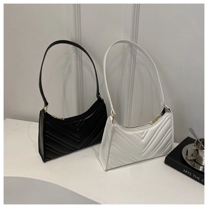 Détail de sacs baguette matelassés en V noir et blanc avec boucles métalliques dorées