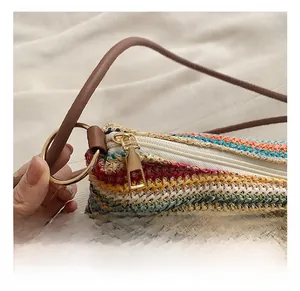 Close-up of rainbow woven tote bag featuring gold hardware zipper and brown strap details