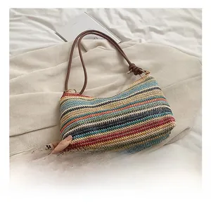 Detail of colorful striped woven straw shoulder bag with brown leather strap and knot