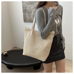 Dettaglio di una grande borsa tote intrecciata beige con manici lunghi per vacanze estive