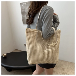 Dettaglio della borsa tote in maglia intrecciata beige portata a spalla per l'estate
