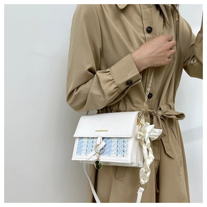 Dettaglio della borsa a tracolla bianca con trama in tweed, foulard e catena oro