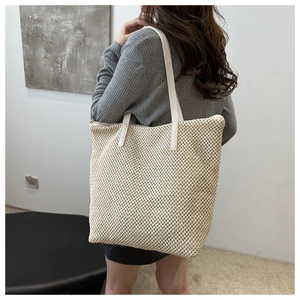 Dettaglio della borsa tote in paglia intrecciata con manici in pelle bianca e trama