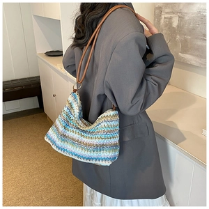 Detail of colorful zigzag woven pattern on a straw shoulder bag with brown leather strap