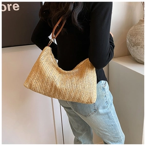 Detail of woven straw hobo bag showing chevron texture and brown leather shoulder strap