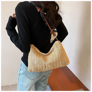 Detailed view of woven straw tote texture with brown leather knotted shoulder strap