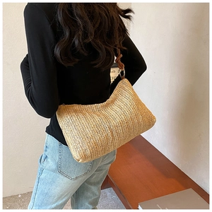 Detail view of woven straw tote bag with braided knot shoulder strap and metal ring