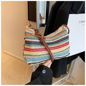 Detailed shot of rainbow striped woven tote bag featuring a brown leather strap and zip closure