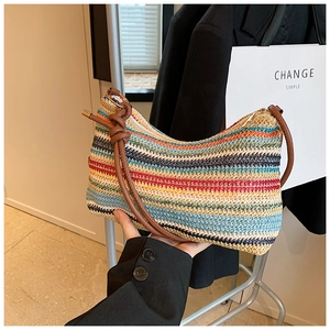 Detail of colorful rainbow striped straw tote bag with brown leather strap and gold zipper