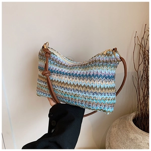 Detail view of colorful woven tote bag showing texture, brown strap and metal ring