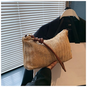 Detail of woven straw tote bag with V-shaped texture and brown knotted leather strap