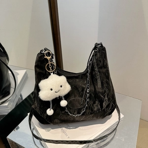 Black ruched shoulder bag with silver chain and white plush cloud charm on books