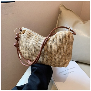 Detail of herringbone straw texture and dark brown leather strap with gold metal ring
