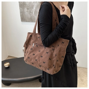 Detail view of brown corduroy tote bag with black bow pattern and side pockets