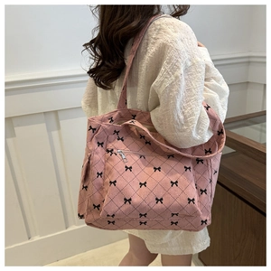 Detail of pink corduroy tote bag with black bow and diamond pattern on model