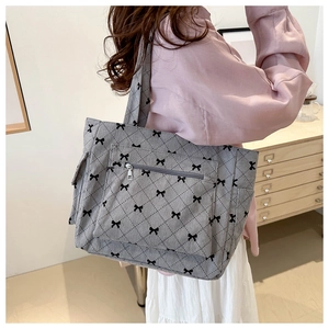 Detail of grey corduroy tote bag with black bow print and front zipper pocket