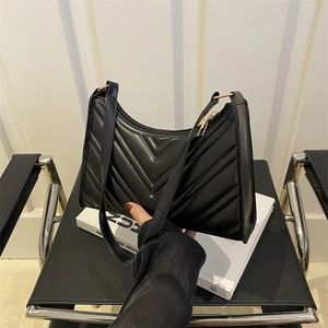 Sac baguette matelassé noir avec coutures en V, fermeture éclair dorée et bandoulière en cuir