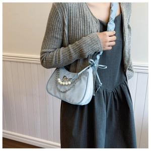 Dettaglio borsa hobo azzurra con catena di perle, fiocco in metallo e tracolla
